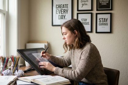 Jeune femme en sweater dessinant sur une tablette num&eacute;rique